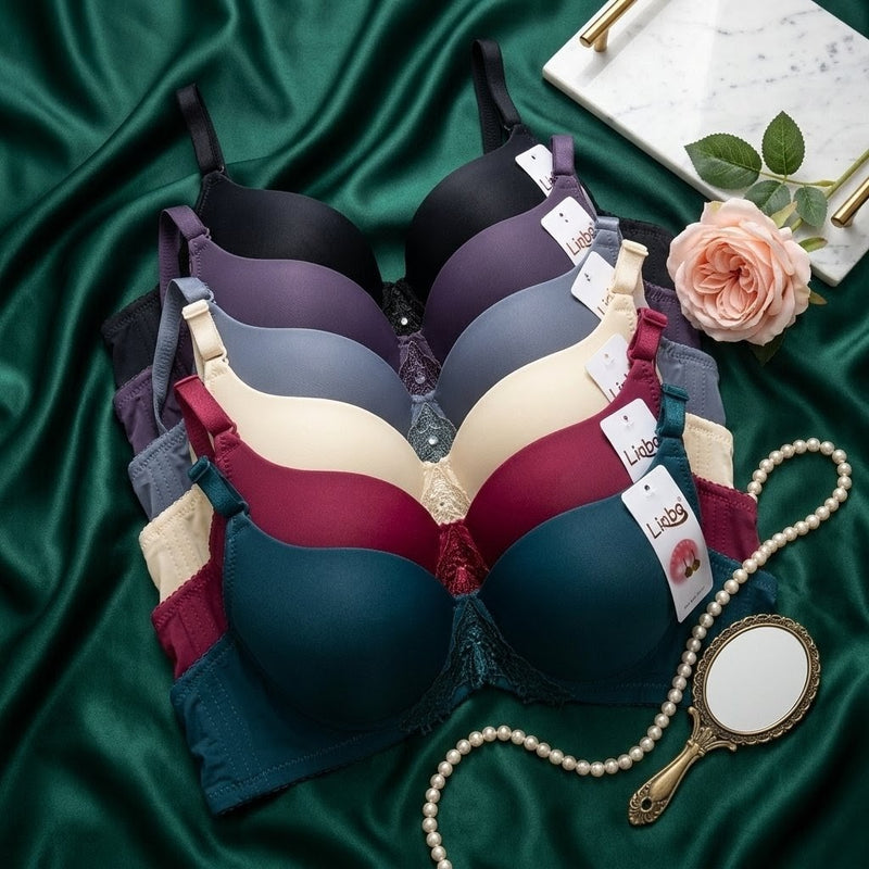 Collection of bras on a green fabric background with a hand mirror and flower.